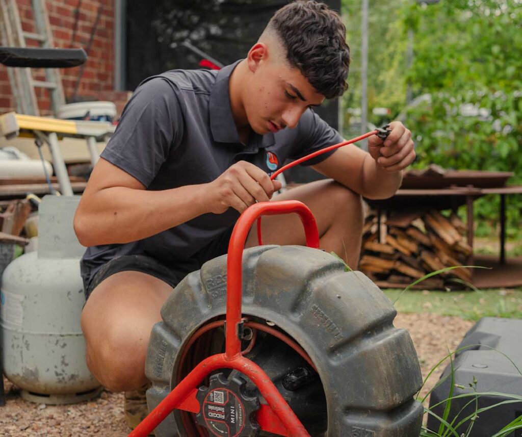 All Spec plumber inspecting pipework beneath a pavement to locate a hidden water leak.